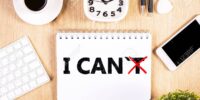 I can, self motivation concept. Crossed out letter 'T so that it reads i can on notepad placed on office desktop with blank smart phone and other items. Mock up